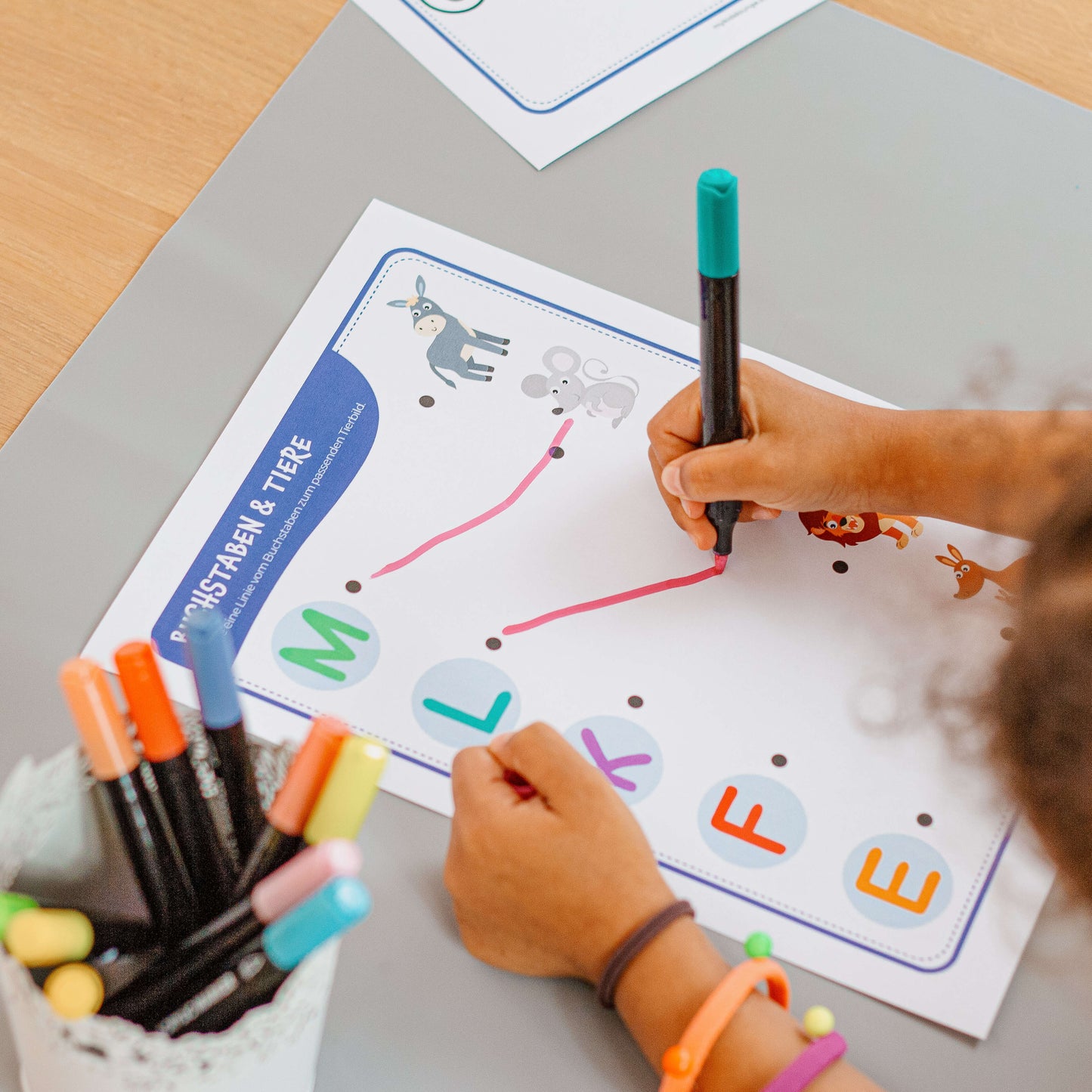 Kind lernt spielerisch Buchstaben und Tiere zuzuordnen – farbenfrohes Lernmaterial zur Förderung der Konzentration und Buchstabenerkennung.