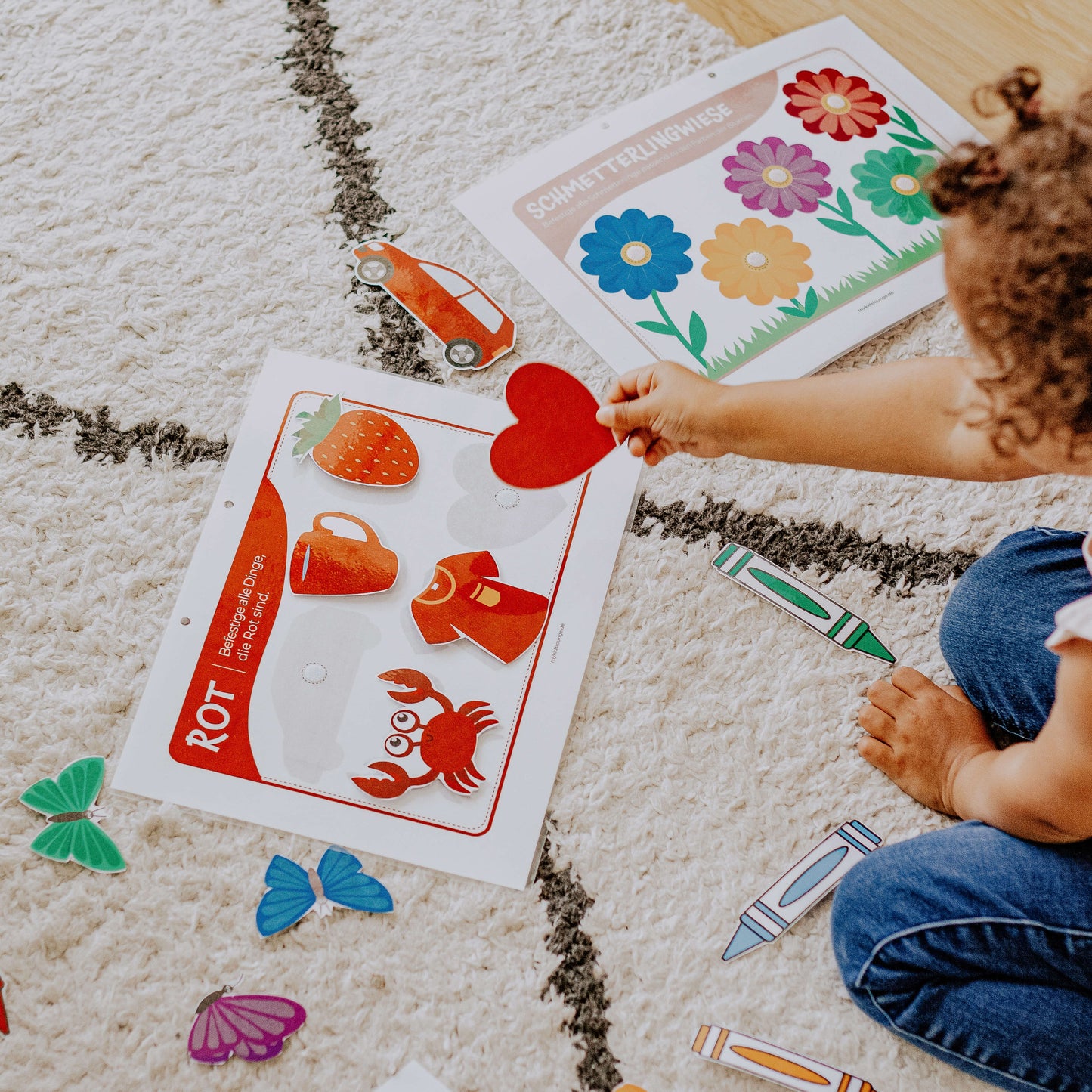 Kind legt DIY Farben lernen Activity Buch auf dem Boden nach