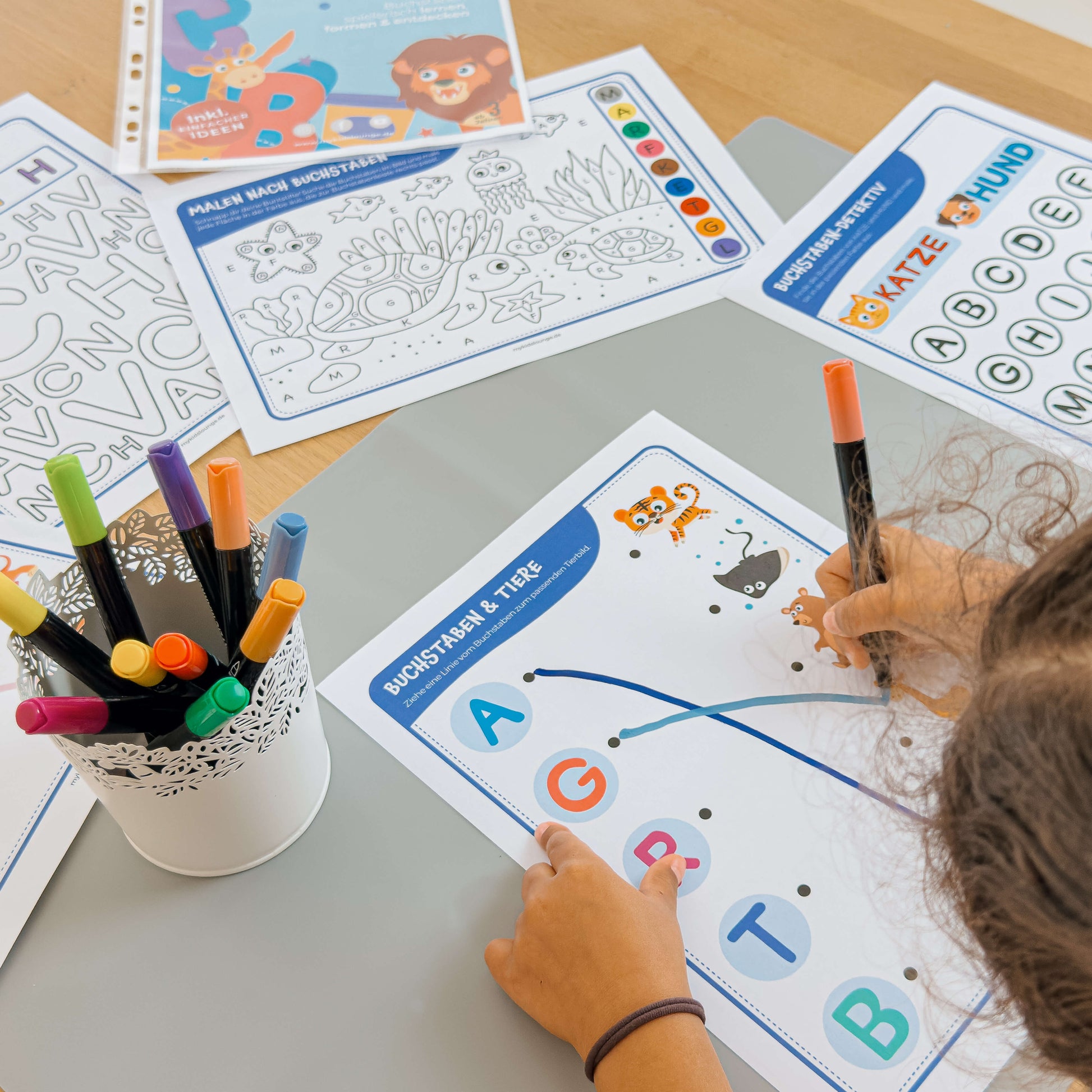 Lernspaß mit Farben und Tieren: Kind verbindet Buchstaben mit den passenden Tierbildern auf einem Arbeitsblatt von mykidslounge.