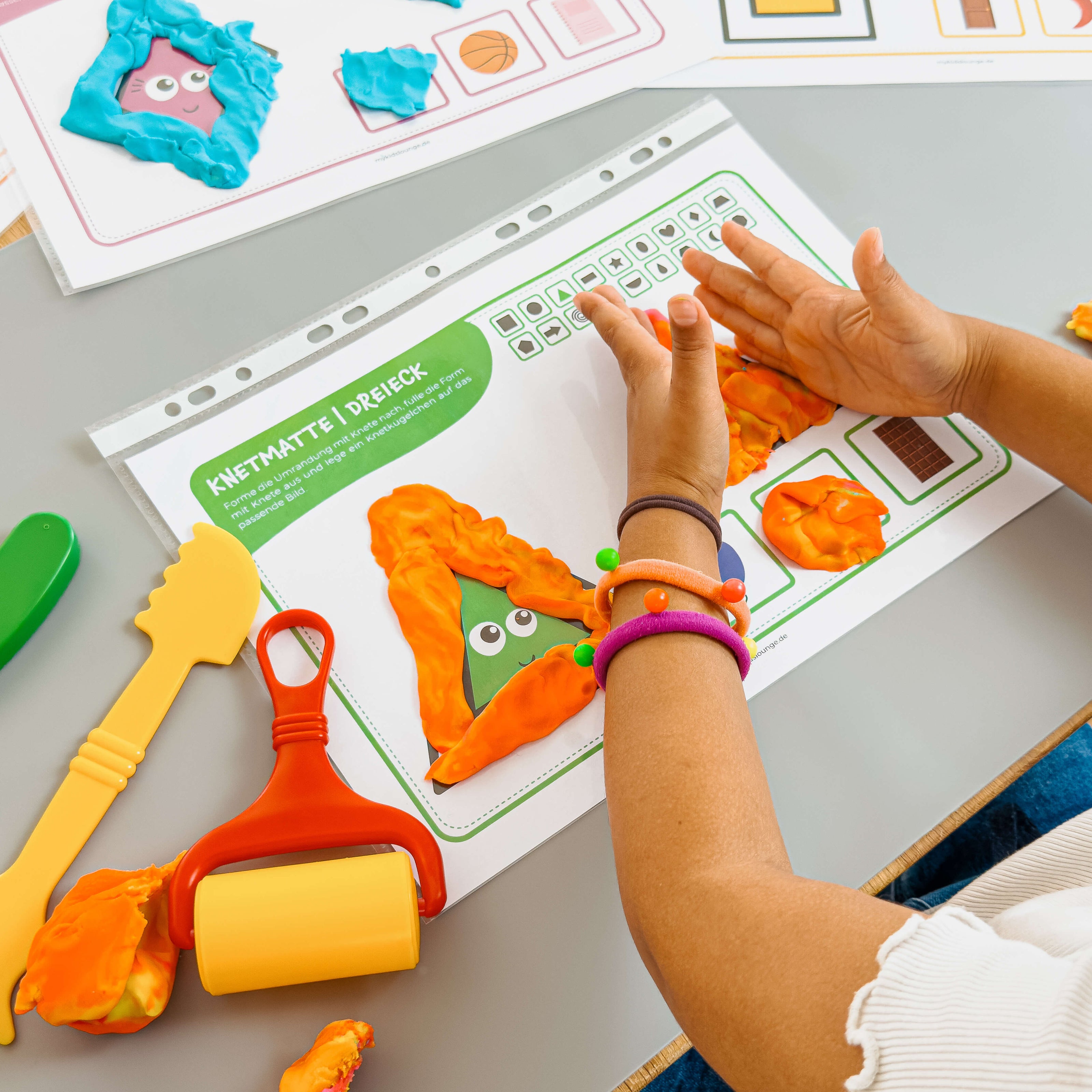 Das Dreieck nimmt Form an – Kind arbeitet konzentriert mit Knete und Werkzeugen auf der Knetmatte von mykidslounge.