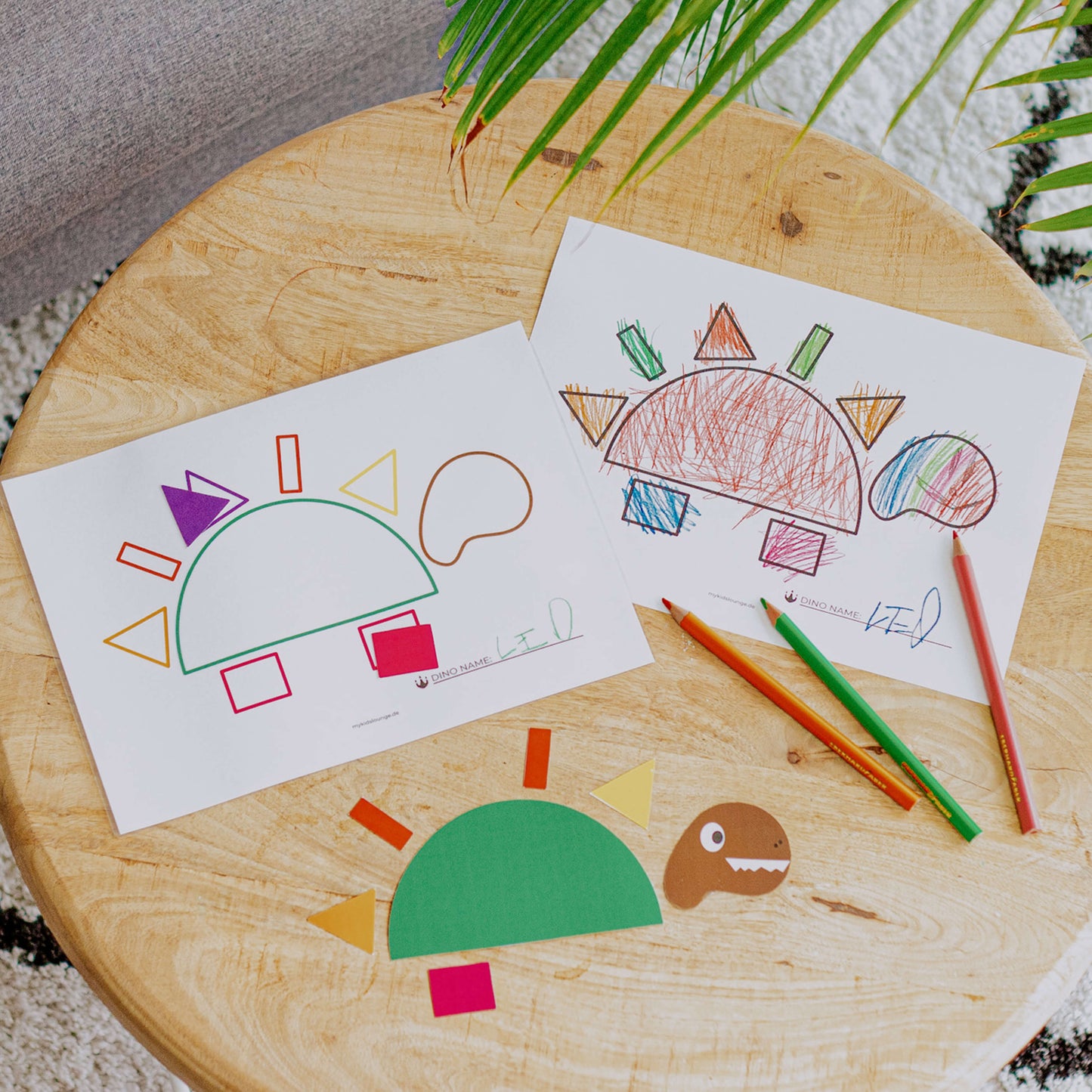 mykidslounge Dinosaurier Druckvorlage liegt mit Buntstiften auf dem Tisch